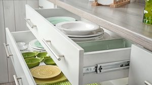 Large kitchen drawers filled with pretty green and white dishes with a headline Declutter Your Home